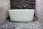 Victoria + Albert IOS bathtub in bathroom with pebble stone floor and hidden drain